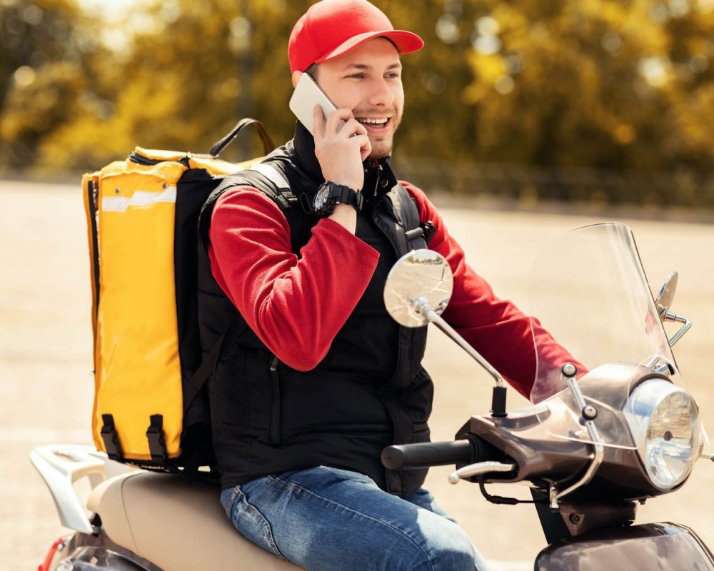 courier-talking-on-mobile-phone-sitting-on-scooter-in-city-1.jpg